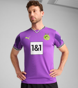 Male model wearing a purple Borussia Dortmund football jersey with neon green crest and 1&1 sponsor, standing with hands on hips.