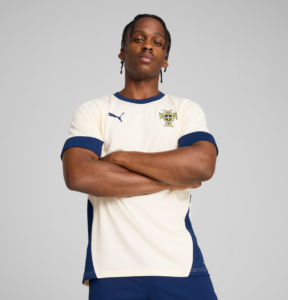 Male soccer player with arms crossed, wearing a cream and blue Portugal jersey.