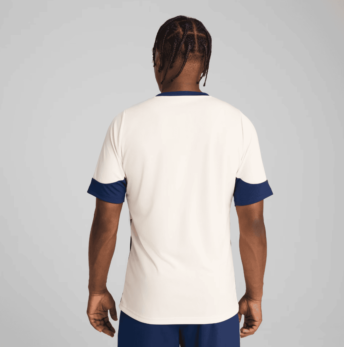Back view of a person wearing a cream sports jersey with navy blue cuffs and collar.
