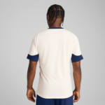 Back view of a person wearing a cream sports jersey with navy blue cuffs and collar.