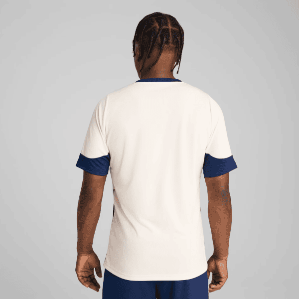 Back view of a person wearing a cream sports jersey with navy blue cuffs and collar.