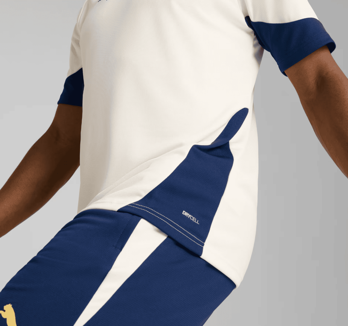 Close-up of a person wearing a white athletic shirt with navy blue side panels and sleeve cuffs, highlighting the fabric and color block design.