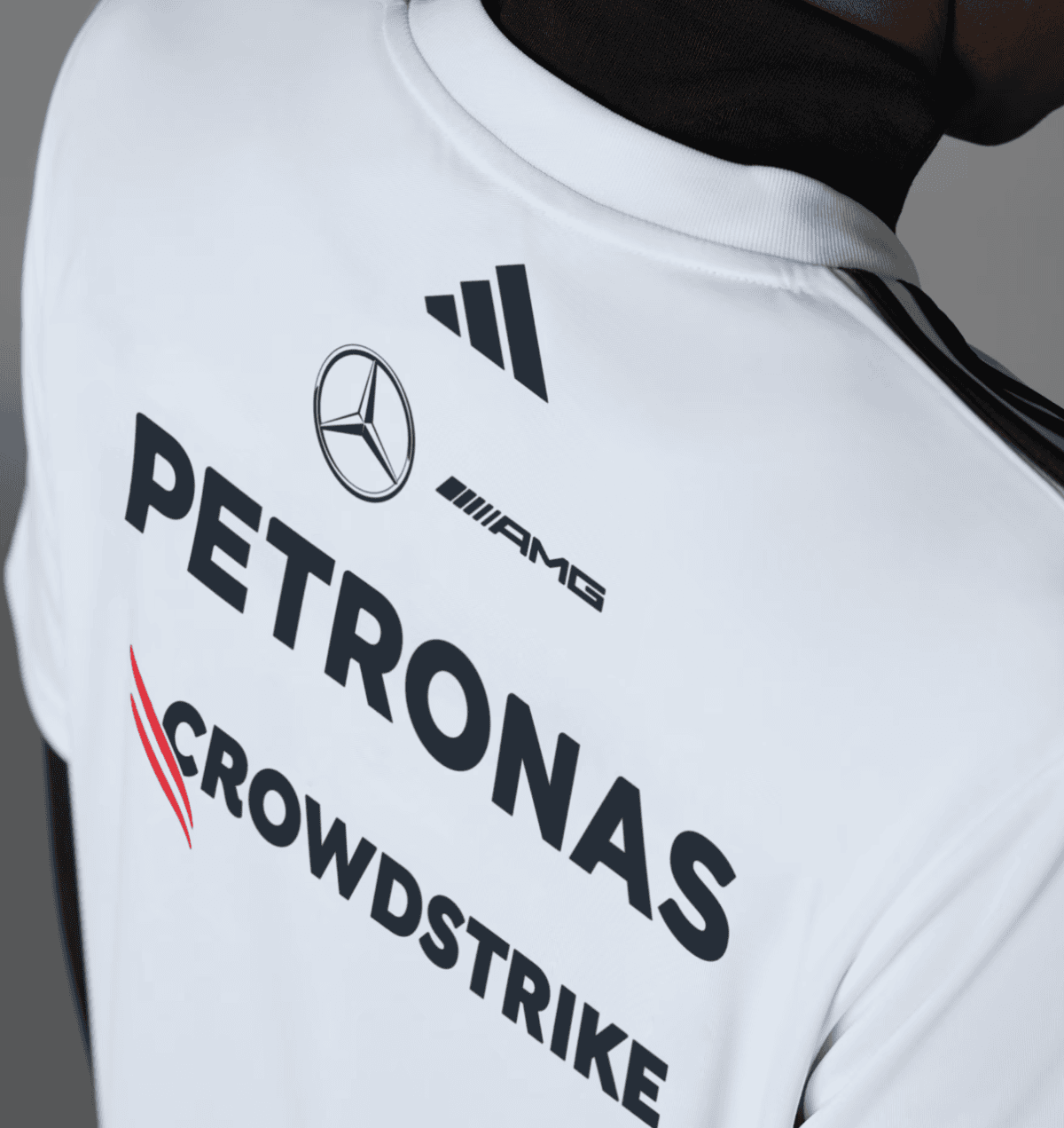 Back of a white sports jersey showing sponsor logos: PETRONAS, Mercedes-Benz, AMG, and CrowdStrike on fabric