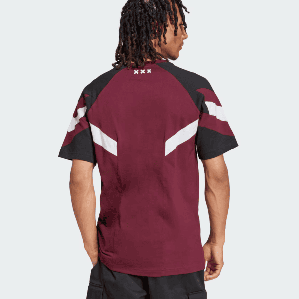 Back view of a man wearing a maroon and black color-block T-shirt with white chevron stripes on the sleeves; four small white X marks near the neckline on the upper back.
