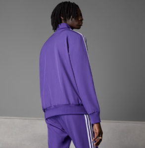 Back view of a person wearing a purple tracksuit with white stripes against a gray backdrop.