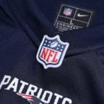 Screenshot_2025-04-17_053034 | UAE SPORT STORE NFL shield pin on a dark blue fabric with 'PATRIOTS' lettering visible below.