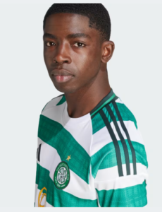 Portrait of a young man wearing a green and white striped soccer jersey with a crest on the chest, looking at the camera.
