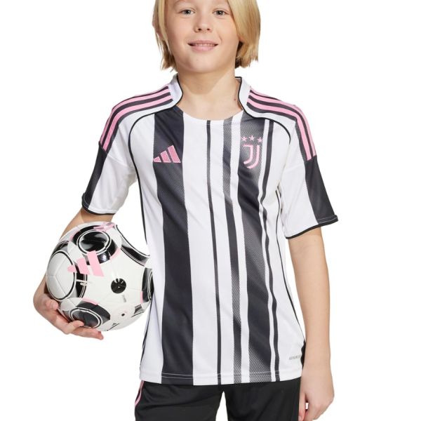 Young girl in a Juventus black-and-white striped soccer kit, holding a soccer ball against a white background.