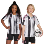 Two young girls in Juventus black-and-white striped soccer uniforms with pink accents, standing against a white background; one holds a soccer ball.