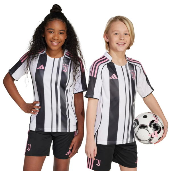 Two young girls in Juventus black-and-white striped soccer uniforms with pink accents, standing against a white background; one holds a soccer ball.