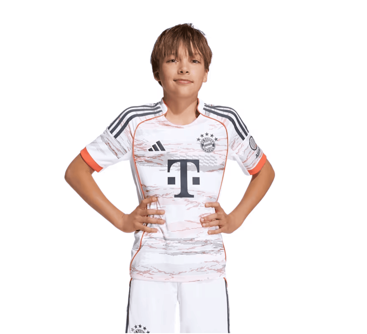 Screenshot_2025-06-19_040732 | UAE SPORT STORE Young boy wearing a white Bayern Munich football jersey with black and orange accents, standing with hands on hips, smiling.