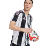 Male soccer player in a black-and-white striped jersey holds a soccer ball against a white background.
