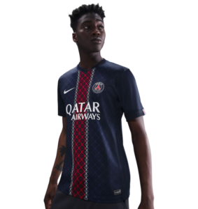 Man wearing a dark blue Paris Saint‑Germain football jersey with a red vertical stripe and Qatar Airways sponsor, posed looking off to the side.