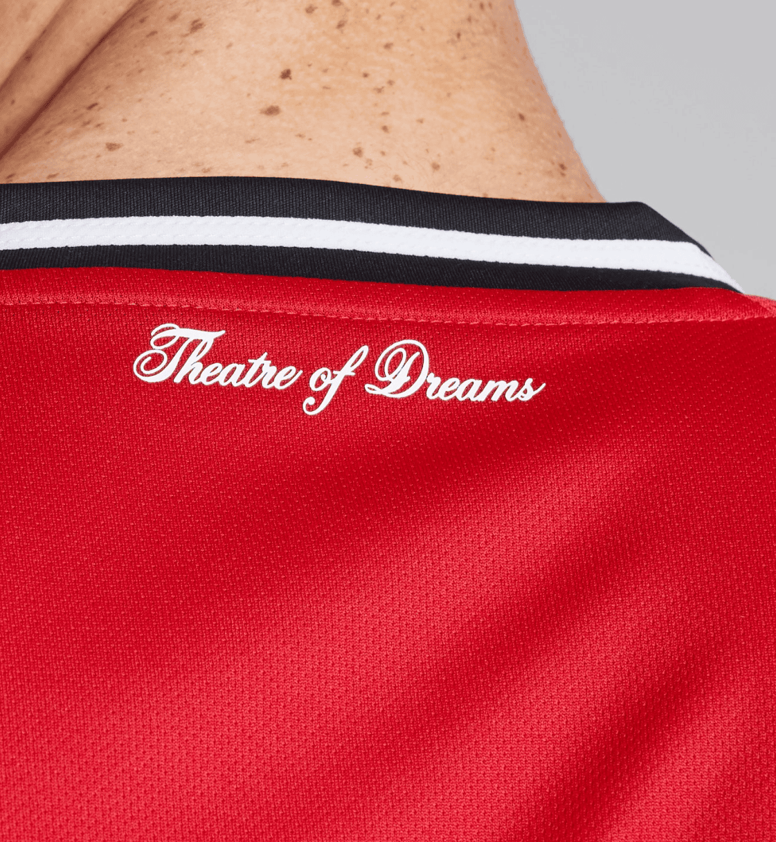 Screenshot_2025-06-23_193718 | UAE SPORT STORE Close-up of a red sports jersey collar with white cursive text 'Theatre of Dreams'.