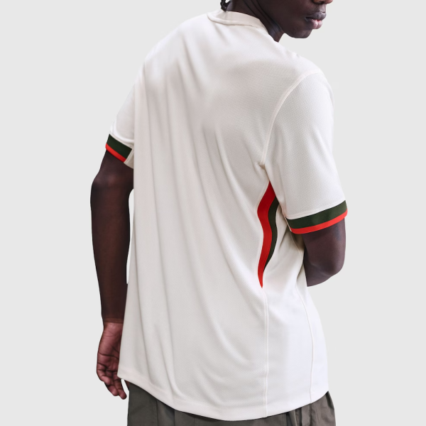 Back view of a person wearing a white athletic polo with red and green stripes on the cuffs and side seam against a light gray background.