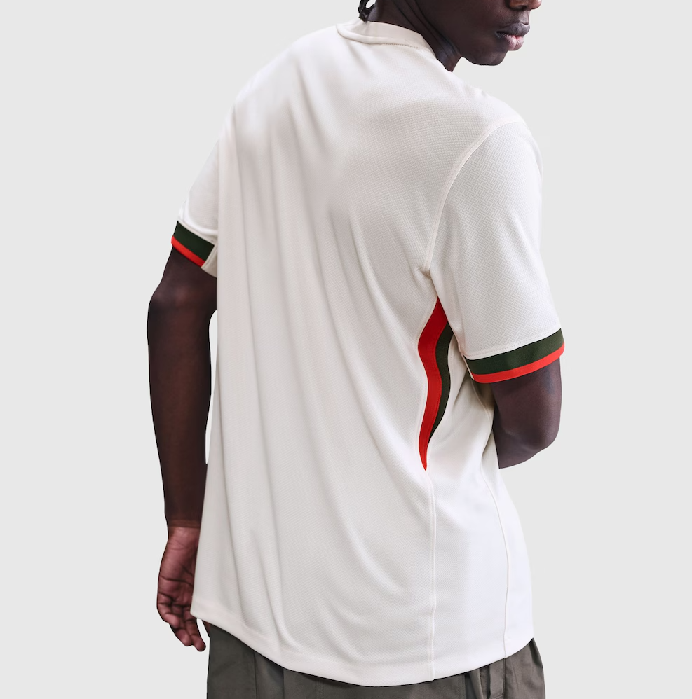 Screenshot_2025-06-23_194608 | UAE SPORT STORE Back view of a person wearing a white athletic polo with red and green stripes on the cuffs and side seam against a light gray background.