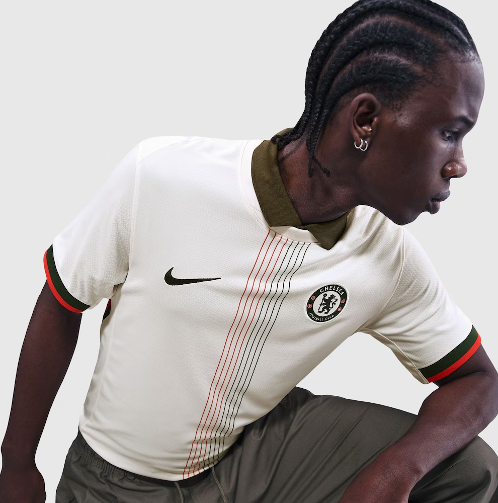 Screenshot_2025-06-23_194633 | UAE SPORT STORE Side profile of a male footballer wearing a Chelsea FC cream jersey with olive collar and red-green sleeve trim, Nike logo visible on chest.
