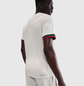 Back view of a person wearing a white athletic T-shirt with green and red trim on the sleeve cuffs.