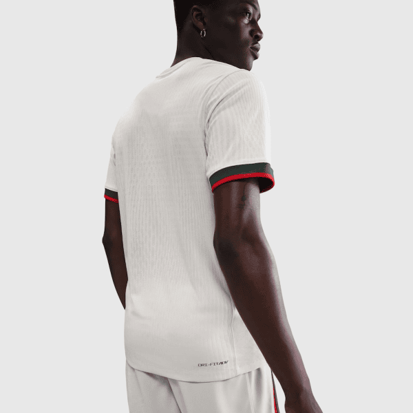 Back view of a person wearing a white athletic T-shirt with green and red trim on the sleeve cuffs.