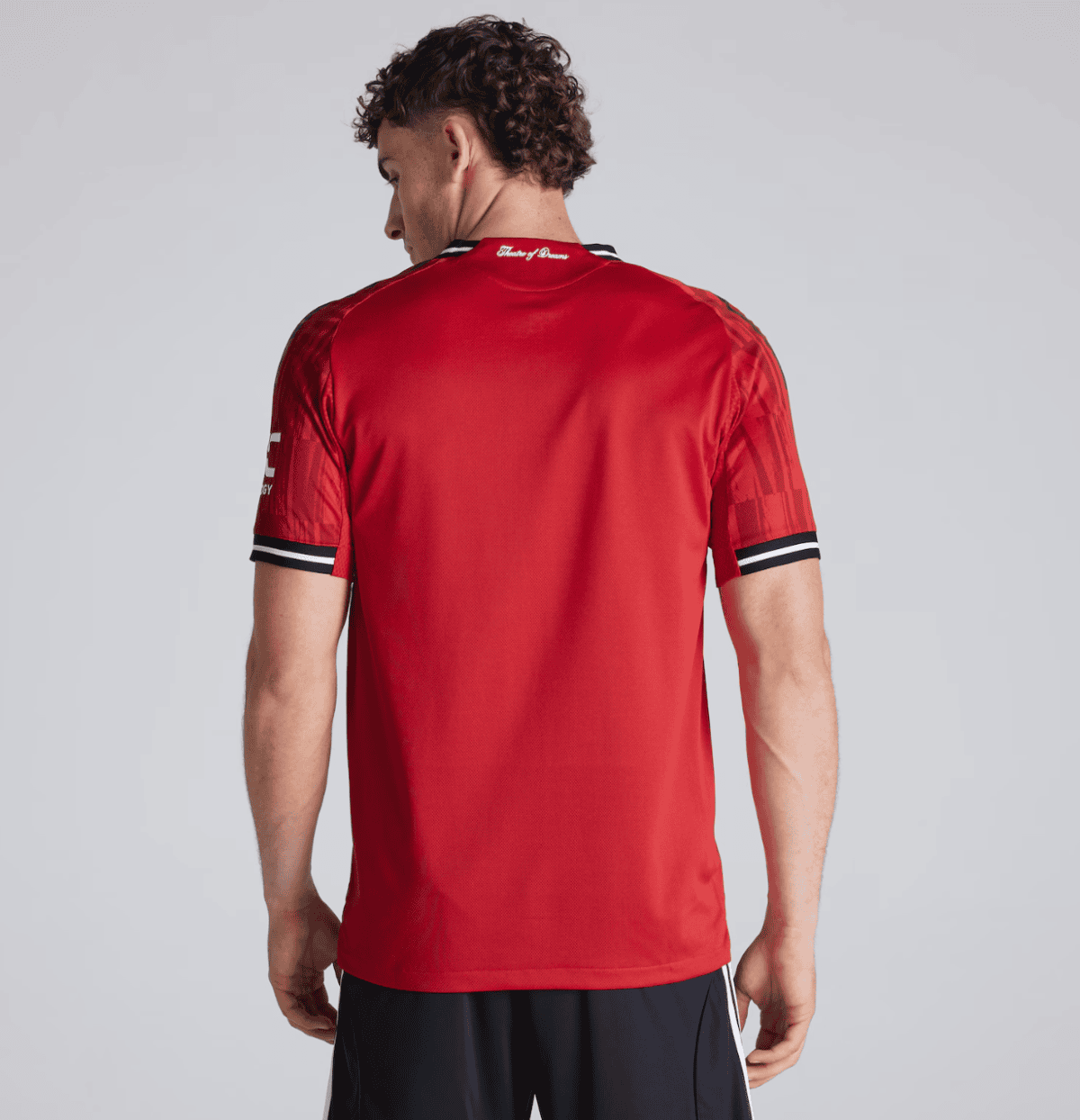 Back view of a man in a red athletic jersey with black-and-white striped cuffs on the sleeves