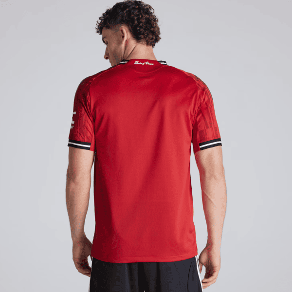Back view of a man in a red athletic jersey with black-and-white striped cuffs on the sleeves
