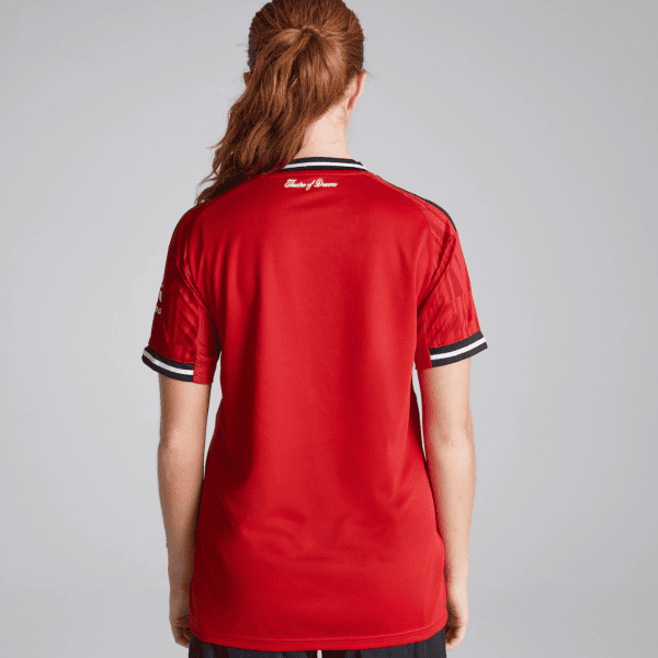 Person standing with back to camera in a red athletic jersey with black-and-white striped collar and cuffs.