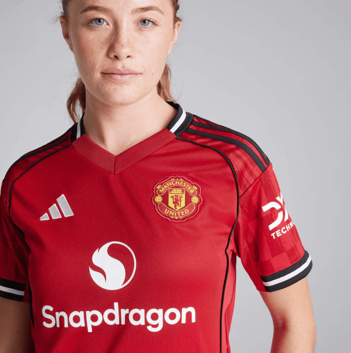 Close-up of a woman wearing a red Manchester United soccer jersey with the club crest and Snapdragon sponsor logo visible on the chest.
