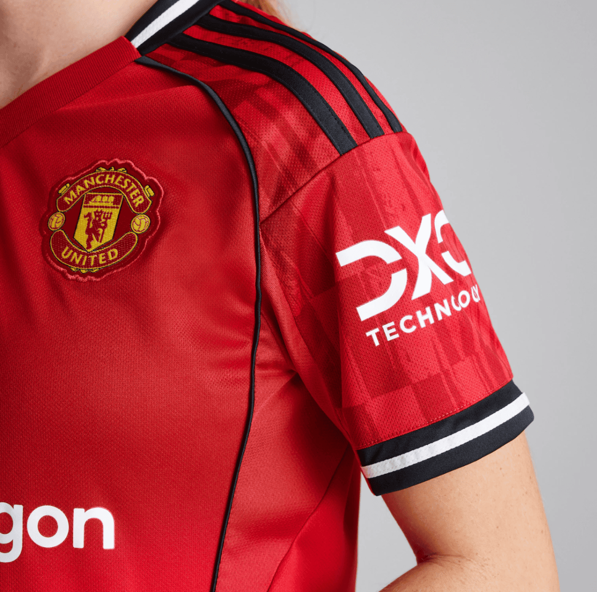 Close-up of a red Manchester United jersey sleeve showing the club crest and DXC Technology logo on the sleeve edge area.