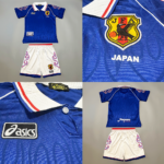 Blue Japan team polo with JFA crest, white shorts with red flame trim and team badge, flat lay collage pieces show front and back views, logos visible.