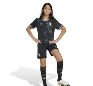Screenshot_2025-10-12_200015 | UAE SPORT STORE Young girl posing in a black Adidas athletic kit (floral pattern jersey and shorts) with hands on hips and striped socks.