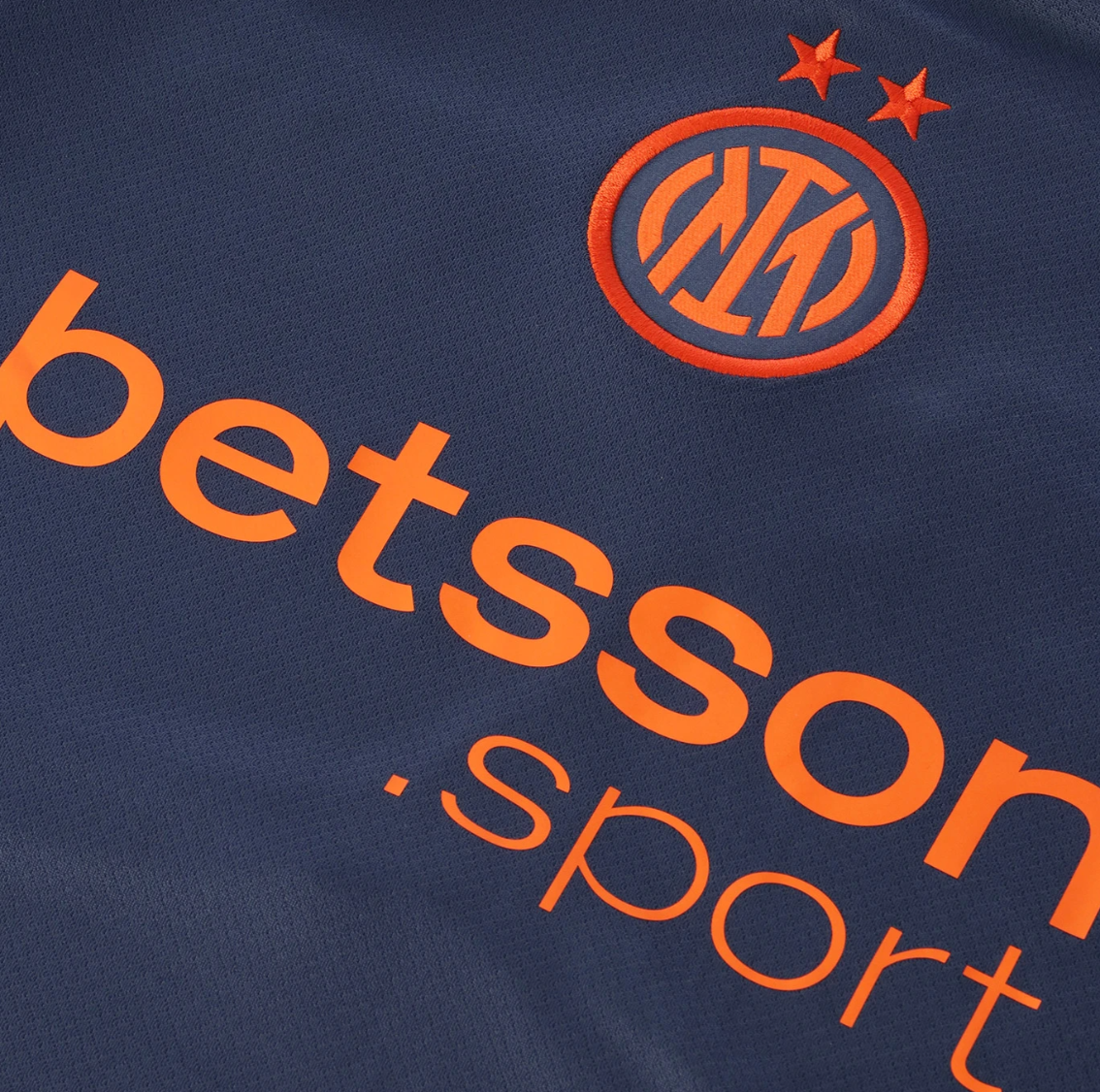 Screenshot_2025-10-12_200457 | UAE SPORT STORE Close-up of a navy Inter Milan jersey with orange sponsor text 'betsson esport' and the club crest with two stars above it.