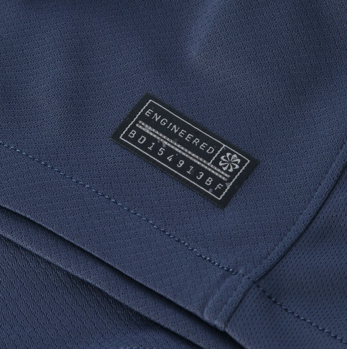 Screenshot_2025-10-12_200509 | UAE SPORT STORE Close-up of dark blue fabric with a small black label reading 'ENGINEERED GARMENTS' sewn onto a pocket seam.