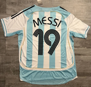 Back view of an Argentina national team soccer jersey with light blue and white vertical stripes, 'MESSI' and number 19 in black