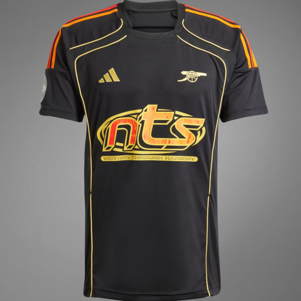Black athletic jersey with orange shoulder piping and gold trim, featuring a large red-yellow 'nts' logo across the chest and a gold emblem on the left chest area.
