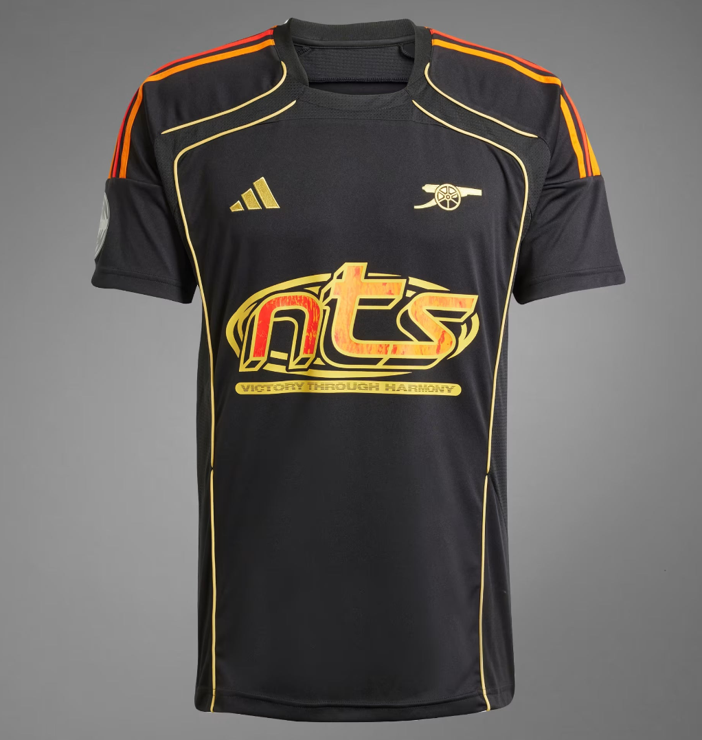 Screenshot_2025-11-05_193854 Black athletic jersey with orange shoulder piping and gold trim, featuring a large red-yellow 'nts' logo across the chest and a gold emblem on the left chest area.