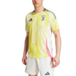 Yellow Juventus football jersey with blue club crest and Adidas logo worn by a male model, white shorts with pink side panels