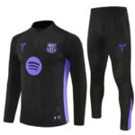 Black FC Barcelona training top with purple accents and matching pants featuring side panels and logos.