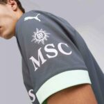Gray athletic sleeve with a white Puma logo and an MSC sun emblem, mint-green cuff visible on the edge.