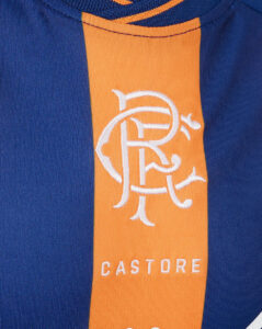 Close-up of a blue jersey with an orange vertical stripe featuring a white intertwined logo above the CASTORE text.