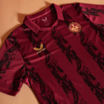 Maroon polo shirt with black striped graphic pattern and gold Castore wing logo on the chest.