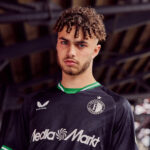 ThRPCyek27MbqNG | UAE SPORT STORE Portrait of a young man with curly hair and a trimmed beard wearing a black Feyenoord football jersey with green trim and Media Markt sponsor.
