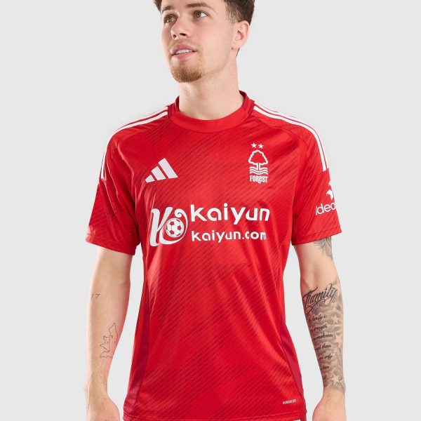 Male model wearing a red Nottingham Forest soccer jersey with white stripes and sponsor logos, looking up and to the left.