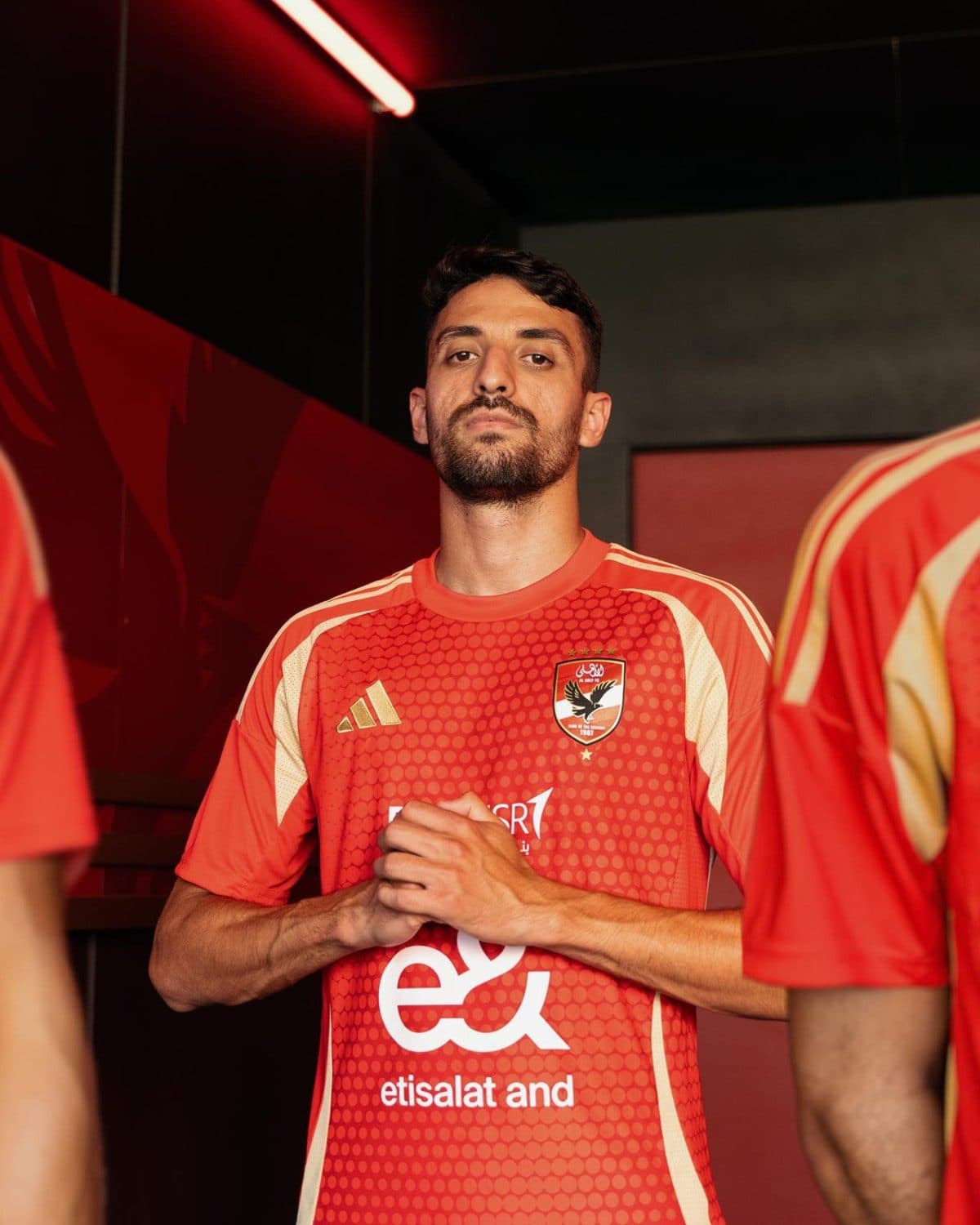 Male soccer player in a red jersey with crest, standing with hands clasped and looking at the camera.