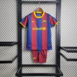 Barcelona football jersey on a hanger with blue and red vertical stripes, UNICEF logo, and yellow Nike swoosh, paired with matching shorts on a rack.