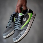 Gray Nike sneakers with a neon green swoosh, held by a hand; close-up of laces, toe stars, and side details for a product shot