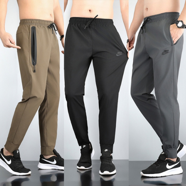 Three pairs of men's Nike jogger pants in brown, black, and gray modeled in a row; features include drawstrings and zip pockets at the sides.