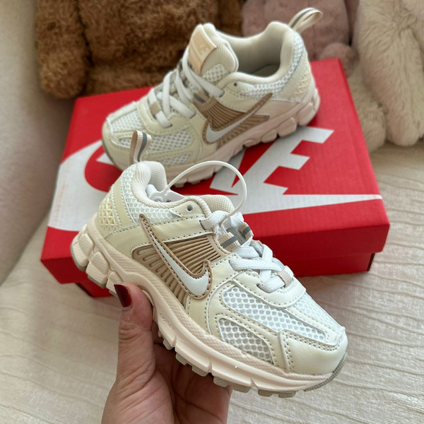 Cream-colored Nike sneakers with mesh panels resting on a red Nike shoebox in the background.