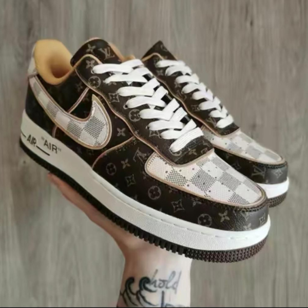 Pair of brown and white patterned sneakers with white laces, held in a hand.