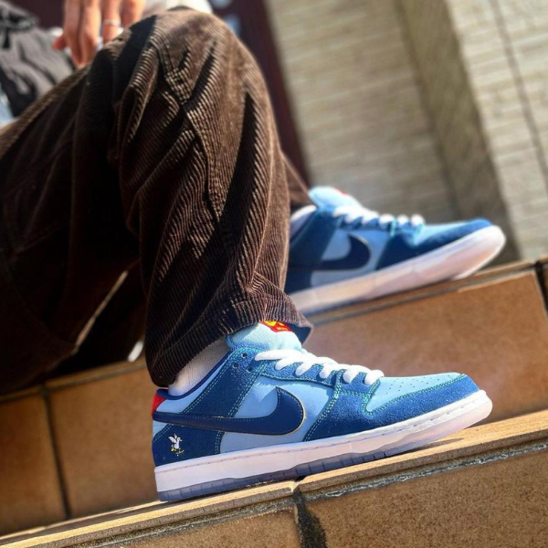 Person wearing blue Nike sneakers with white laces stepping down brown corduroy pants on tiled stairs, urban setting