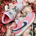 Pink children's sneakers with glittery '23' accents on the strap, set among pink roses.